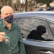 photo of a senior man standing outside the driver's side door of a car, holding the keys up