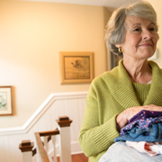 a smiling senior woman with a stack of folded clothes in her hands