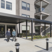 senior independent living couple walking out of an apartment CCRC with their dog