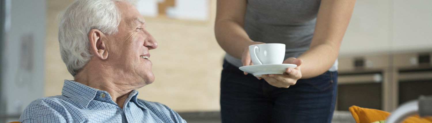 person handing a senior a cup of coffee