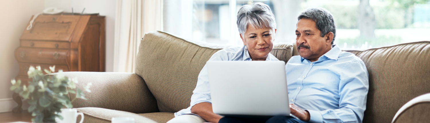 senior couple on a couch looking at a laptop