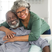 photo of a happy senior couple sitting on a couch smiling