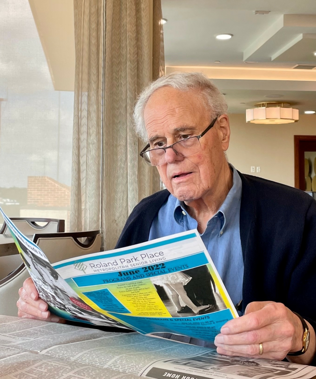 senior reading the Roland Park Place newsletter
