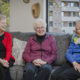 three senior women sitting together on a couch and smiling