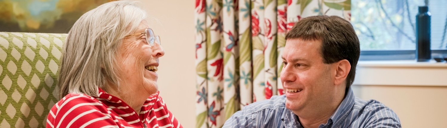 Image of a laughing senior woman with a younger male family member or friend. 