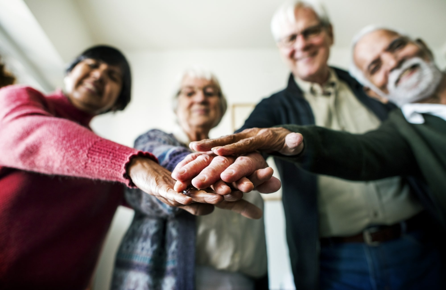 Image of a group of happy seniors with hands together.