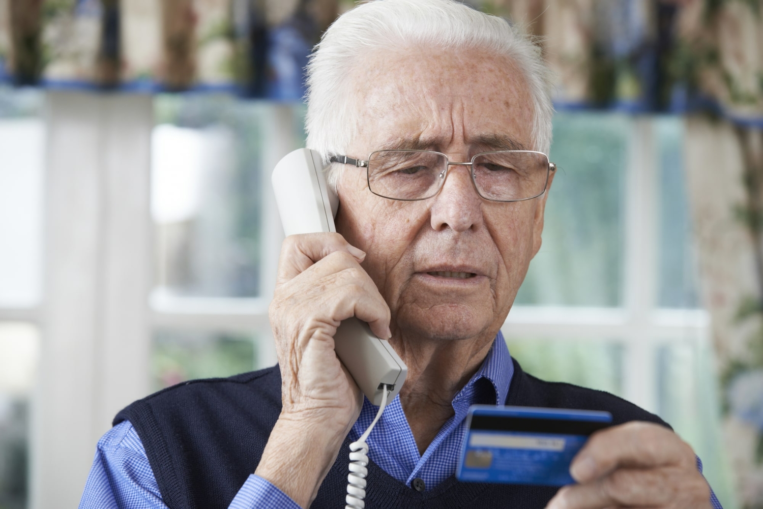 Senior man giving credit card details over the phone.