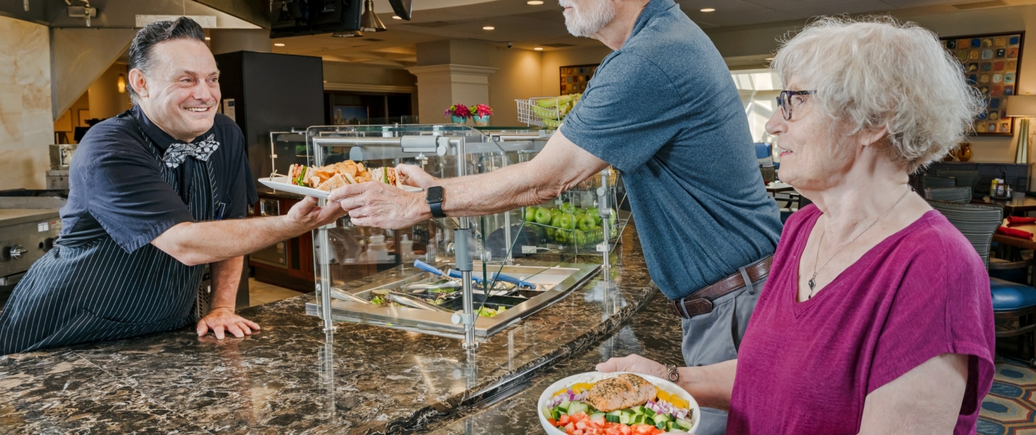 a senior couple getting food from Neighbors’ Bistro, one of the dining options at Roland Park Place senior living community in Baltimore