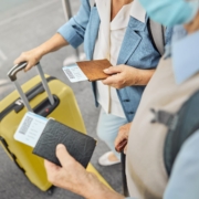 close up overhead shot of hands of traveling senior couple standing outside the airport with passports and luggage